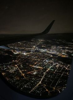 the view from an airplane window at night, looking down on a cityscape