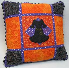 an orange and purple pillow with a black witch on it