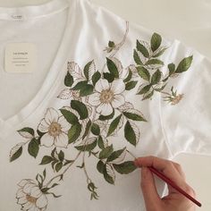 a person is drawing flowers on a t - shirt