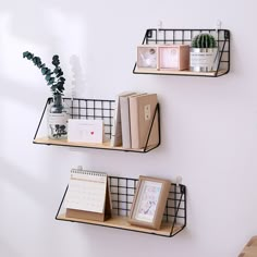 two black metal shelves with books and pictures on them next to a wall mounted planter