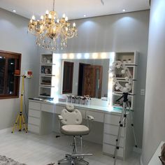 a white chair sitting in front of a vanity with a chandelier hanging from it's ceiling