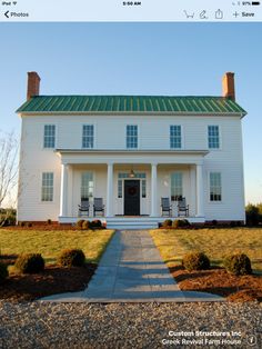 a large white house sitting on top of a lush green field