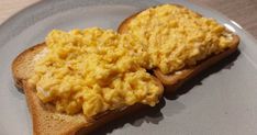 two pieces of toast with scrambled eggs on them