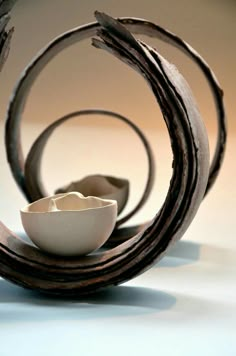 a white bowl sitting on top of a table next to a wooden piece of art