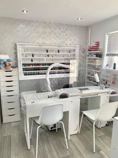 a white desk sitting in front of a window filled with lots of drawers and shelves