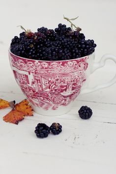 blackberries in a red and white cup with leaves