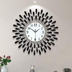 a clock that is on the side of a wall next to some vases and flowers