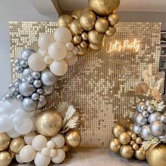 gold and silver balloons are on display in front of a wall with the words let's party