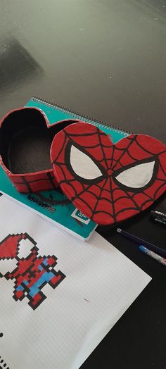 a spiderman shoe sitting on top of a table next to some markers and pencils