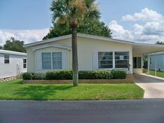 a mobile home sits on the corner of a street in front of a palm tree