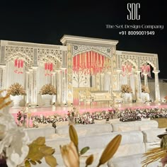 an elaborately decorated stage with flowers and greenery in front of it at night