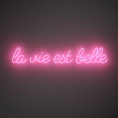 a neon sign with the words la vie est belle in pink on a black background