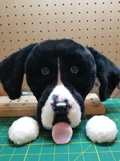 a black and white dog with its tongue out sitting on a green cutting board next to a wooden object