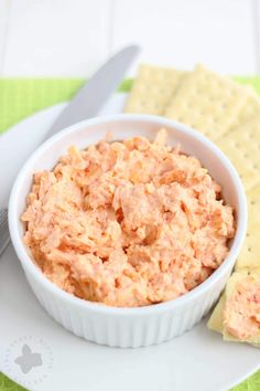 a white bowl filled with dip next to crackers