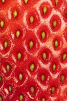 a close up view of the inside of a strawberry with green seeds on it's surface