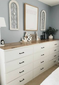 a white dresser with drawers and pictures on the wall