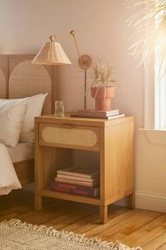 a bedroom with a bed, nightstand and plants on the night stand next to it