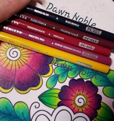 four different colored pencils sitting next to each other on top of a flowered surface