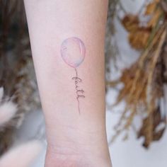 a small balloon tattoo on the wrist