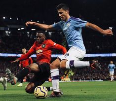 two men playing soccer on a field with fans in the stands watching from the stands