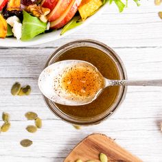 a salad with dressing in a glass bowl next to a wooden cutting board and spoon