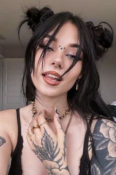 a woman with tattoos and piercings on her chest posing for the camera while wearing a black top