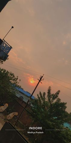 the sun is setting over some trees and buildings