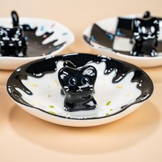 two black and white plates with cat figurines on them