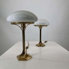 two white and gold lamps sitting on top of a table