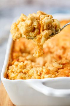 a spoon full of macaroni and cheese being lifted from a casserole dish