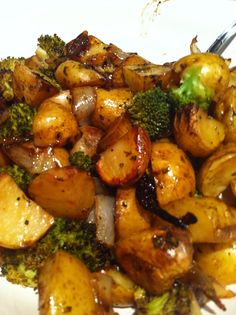 a white plate topped with potatoes and broccoli covered in sauce next to a fork