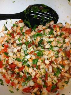 a white bowl filled with chopped vegetables and a black spoon