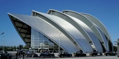 a large building with cars parked in front of it and people walking around the outside