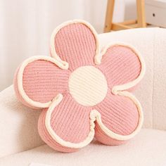 a pink flower pillow sitting on top of a white couch