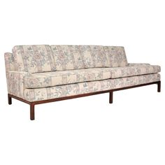 a couch that is sitting on top of a wooden frame and has floral print upholster