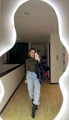 a woman taking a selfie in front of a mirror with her hand on her hip