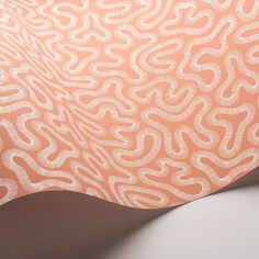 an orange and white wallpaper with wavy lines on it's surface, as well as the back end of a chair