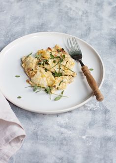 a white plate topped with an omelet and a fork next to a napkin