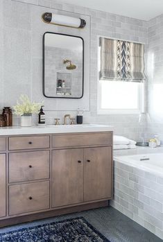 a bathroom with a sink, mirror and bathtub next to a window in it