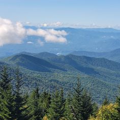 the mountains are covered in clouds and trees