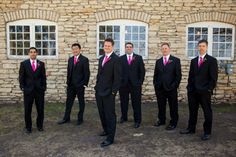 a group of men standing next to each other in front of a brick building with windows