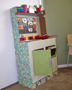 a child's play kitchen in the corner of a room next to a chair