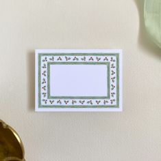 a white card with green border and red berries on it next to a potted plant