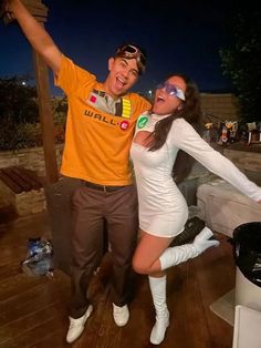 a man and woman dressed in costumes posing for a photo on a deck at night