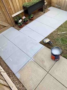 a backyard area with cement pavers and paint bucket