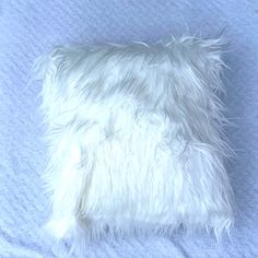 a white furry pillow on a blue blanket