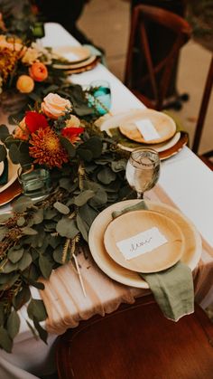 the table is set with plates and place settings for guests to sit down at it