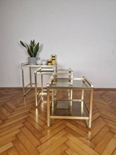 three tables sitting on top of a wooden floor next to a plant in a vase