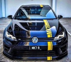 the front end of a black volkswagen car with yellow stripes on it's hood