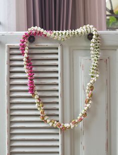 a white door with pink and green flowers on it's side, next to a window